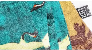 Macro shot of twill polyester fabric showing detailed crane print and wash care label
