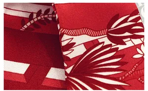 Detail of red silk scarf with tropical leaf print and fine twill weaving texture