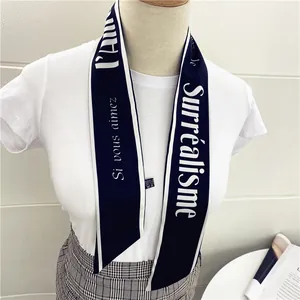 Detalle de pañuelo azul marino con texto francés blanco sobre camiseta blanca y falda