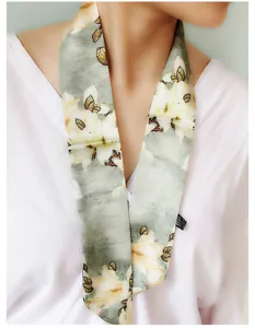 Detail shot of magnolia floral print silk scarf worn with a white V-neck blouse