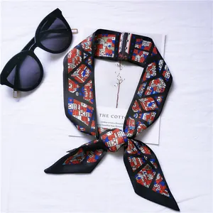Detail view of a long silk-feel neck scarf featuring a colorful geometric building print