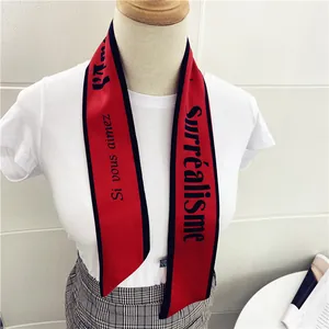 Detalle de pañuelo de seda rojo con estampado de surrealismo anudado al cuello con estilo
