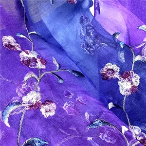 Dettaglio ricamo floreale viola su scialle in seta e lana con sfumature di colore