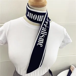 Detalle de un pañuelo de satén negro con texto L'amour blanco sobre una camiseta blanca