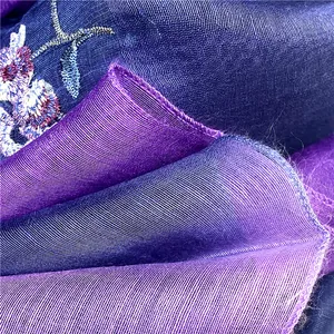 Dettaglio macro della sciarpa in seta e lana ricamata con fiori in sfumature blu viola