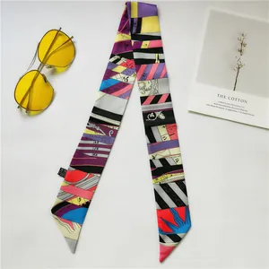 Flat lay of colorful geometric satin twilly scarf with sunglasses and art card styling