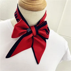 Primer plano de un pañuelo de seda rojo con letras negras anudado en un maniquí de moda