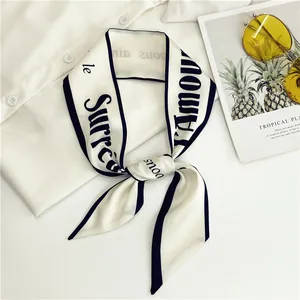 Detalle de un elegante pañuelo twilly blanco de estilo francés con letras y bordes negros