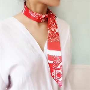 Red narrow silk scarf twilly with geometric patterns tied around a model neck