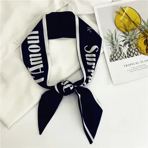 Detalle de pañuelo de seda azul marino con texto L'Amour blanco sobre una camisa