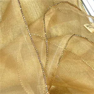 Dettaglio del tessuto in seta dorata con bordi in strass scintillanti per sciarpe eleganti