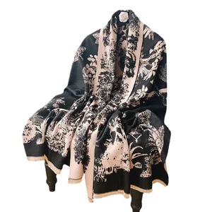 Châle élégant aspect cachemire avec motif floral noir et rose sur une chaise en bois