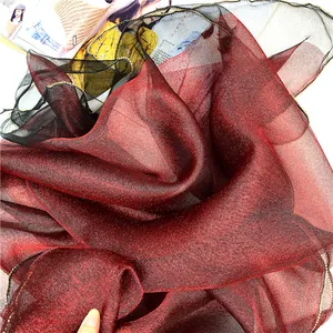 Dettaglio della sciarpa in seta e lana con sfumatura rosso-nera, glitter e bordo dorato