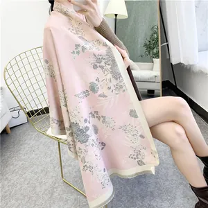 Close-up of pink winter scarf with gray floral patterns and elegant fringe details
