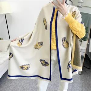 Detail view of large cream shawl with blue and yellow feather prints and tassels