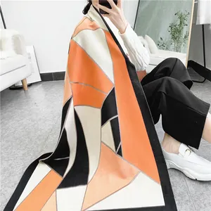 Detail of soft geometric patchwork shawl showing orange, grey, and black patterns