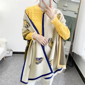 Detail of elegant cream shawl with blue feather print and white fringe tassels