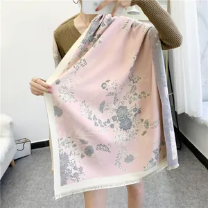 Detail of pink floral cashmere shawl with tassel edges styled on a brown sweater