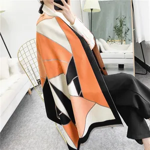 Close-up of geometric pattern knit scarf with fringe details in orange and grey