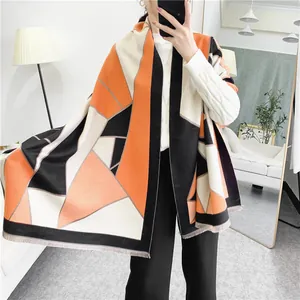 Detail of soft geometric patterned pashmina shawl with tassel edges in orange and black