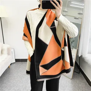 Close-up of geometric color block shawl with orange and black patches and fringe detail