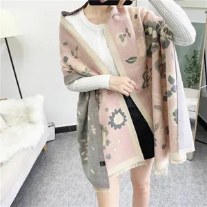 Détail d'une écharpe bohème à fleurs roses et vertes avec des franges fines et texture douce