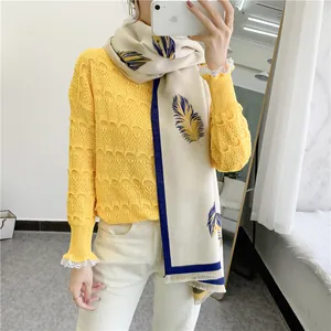 Detailed close-up of a warm beige scarf featuring blue and yellow feather patterns