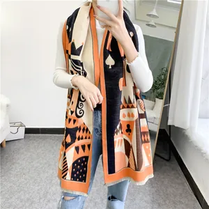 Detail of thick winter scarf featuring poker patterns with orange and black fringe edges