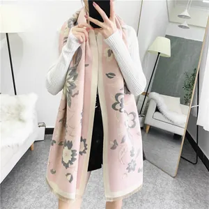 Détail d'une écharpe d'hiver bohème rose avec motifs floraux gris et bordure à franges