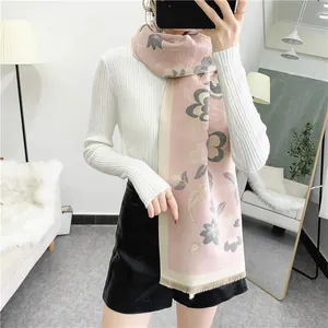 Détail d'une écharpe bohème en cachemire rose et blanc avec fleurs et franges