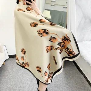 Detail of elegant beige cashmere-like shawl with orange tulip prints and black fringe trim