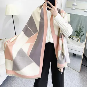 Detail of thick geometric patchwork scarf with soft pink and grey tones and fringe trim