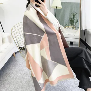 Detail view of geometric patchwork shawl scarf with grey, cream, and pink soft cashmere-like fabric