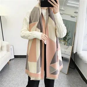 Close-up of thick geometric patchwork scarf with fringe details in pink and grey
