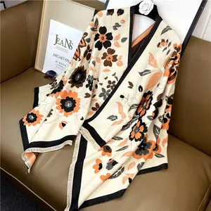 Détail d'un châle bohème en maille avec imprimé floral et franges sur canapé cuir