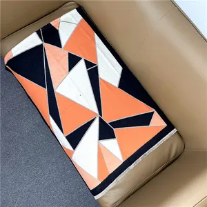 Close-up of geometric orange and black cashmere shawl with detailed fringe edges