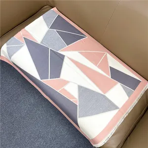 Detail of soft geometric patterned shawl with fine tassels on a brown leather sofa