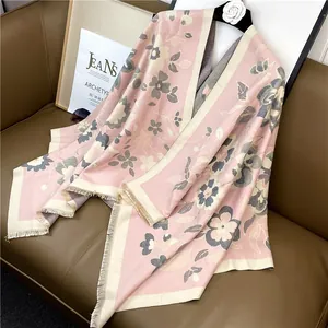 Détail d'une écharpe d'hiver bohème rose avec d'élégants pompons à franges beige