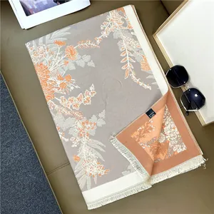 Detailed macro view of the grey and orange floral jacquard scarf with soft fringe trim