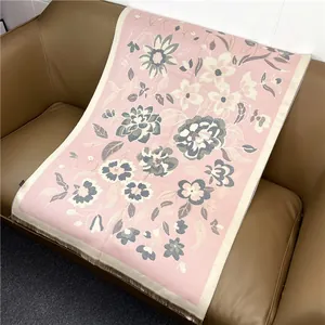 Détail d'une écharpe bohème rose à fleurs avec franges sur un canapé en cuir