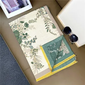 Detail of floral cashmere-style scarf featuring yellow tassels and green leaf patterns