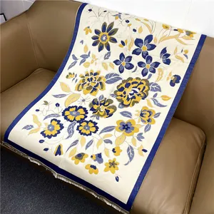 Détail d'une écharpe fleurie en maille beige avec bordures à franges bleu foncé élégantes