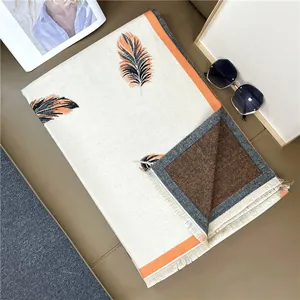 Detailed view of cream feather print scarf with fringe edges and soft woven texture