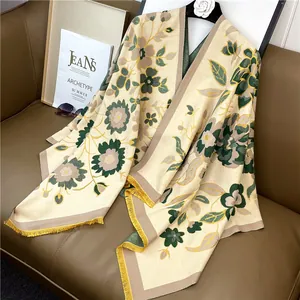 Détail d'une écharpe en cachemire beige avec fleurs vertes et franges jaunes sur sofa