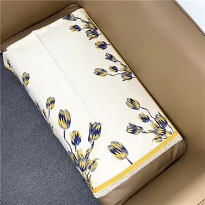 Detailed view of the tulip floral pattern and delicate white fringe on an ivory shawl