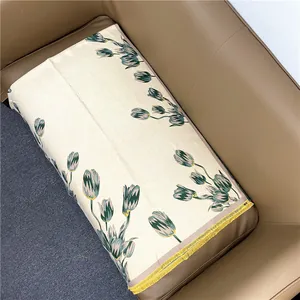 Detail of tulip floral patterns on soft cream scarf with yellow fringe on leather sofa