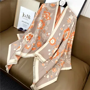 Vue détaillée du pashmina bohème avec des fleurs orange et des pompons à franges
