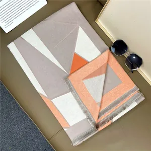 Close-up of thick geometric color-block scarf with orange and grey weave and fringe trim
