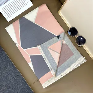 Detail of geometric pink and grey scarf with tassels and small black brand label