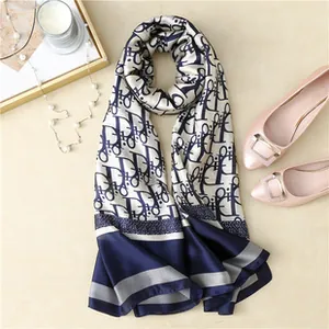 Detailed close-up of a long silk-feel scarf with blue oblique pattern and elegant props